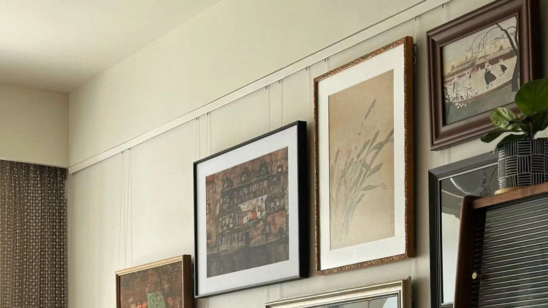 Gallery wall of framed pictures hung from a picture rail track with cables and hooks