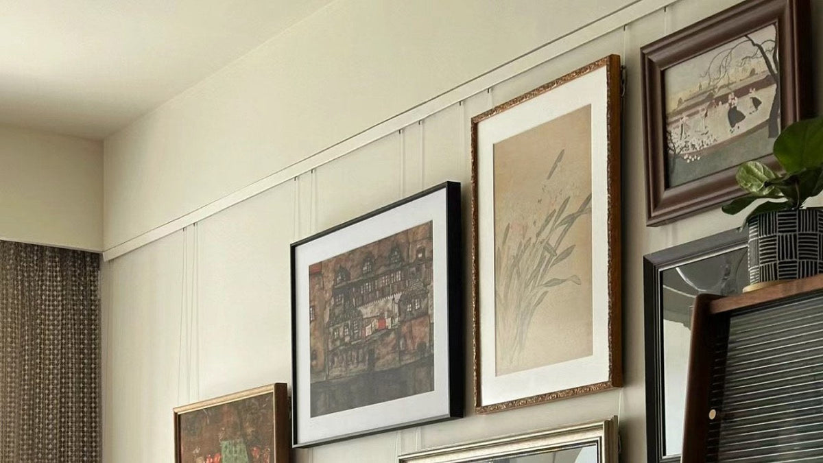 Gallery wall of framed pictures hung from a picture rail track with cables and hooks